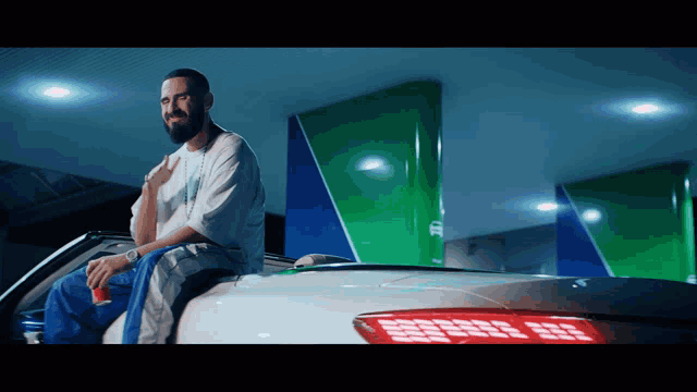 a man is sitting on the back of a white car