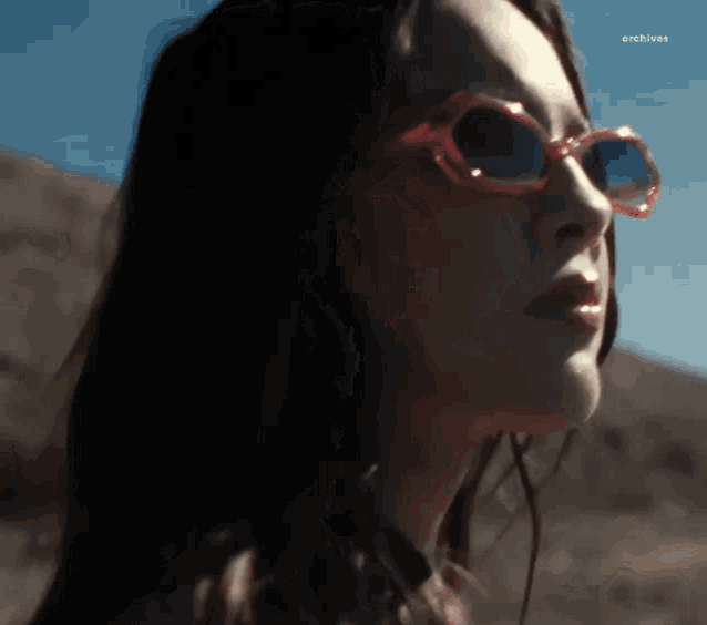 a close up of a woman wearing sunglasses with the word archives visible in the corner