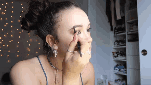 a woman applies makeup to her eyebrows with a brush