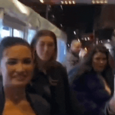 a group of people are standing next to each other on a bus and smiling .