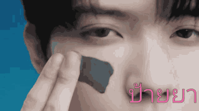 a close up of a person applying a mask to their face with a blue background