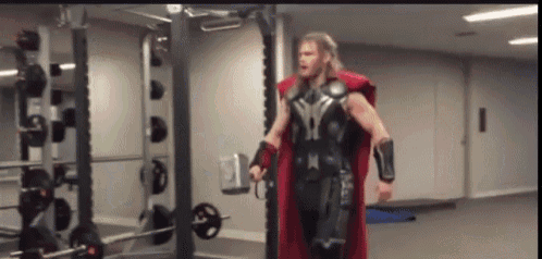 a man dressed as thor is standing in a gym holding a barbell