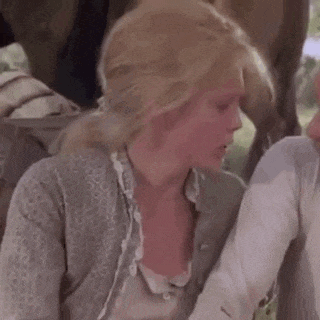 a woman is sitting next to a man in a field .