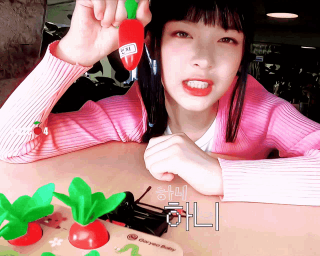 a girl in a pink sweater is holding a tomato with a label that says ' pai ' on it