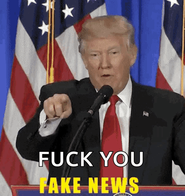 donald trump giving a speech with the words fuck you fake news behind him