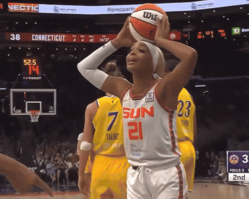 a female basketball player with the number 21 on her jersey is about to shoot the ball
