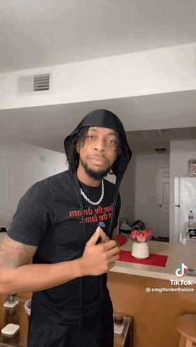a man wearing a black t-shirt and a headband is standing in a living room .