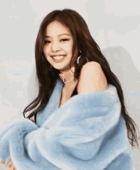 a young woman wearing a blue fur coat and a choker is smiling .