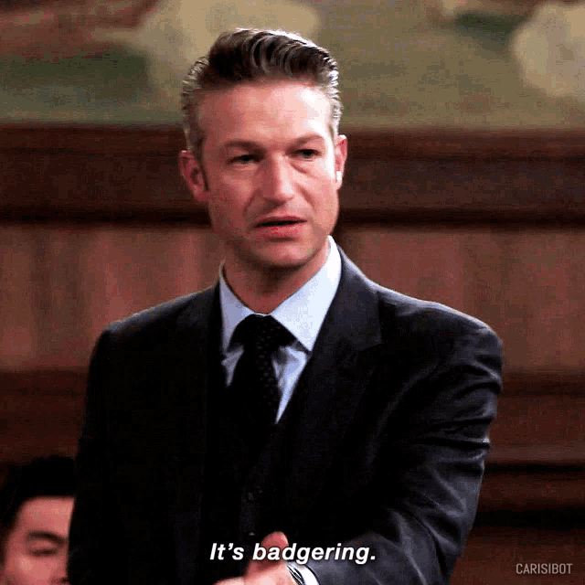 a man in a suit and tie is saying " it 's badgering "