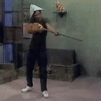 a woman wearing a triangle hat is holding a broom in a room .