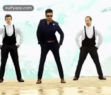 a group of men are standing next to each other on a beach and dancing .