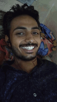 a man with a beard and mustache is smiling while laying on a bed