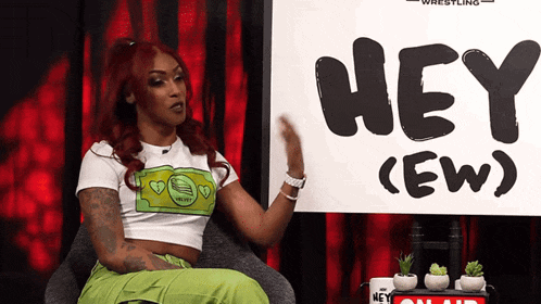 a woman sitting in front of a sign that says hey (ew )
