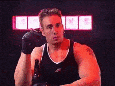 a man is smoking a cigarette while holding a bottle of beer and wearing gloves .