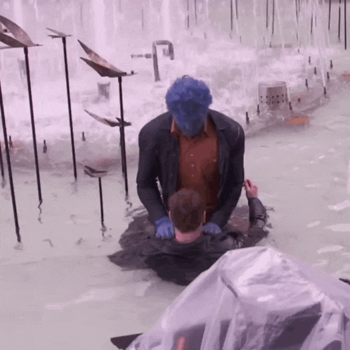 a man with blue hair is kneeling in a pool