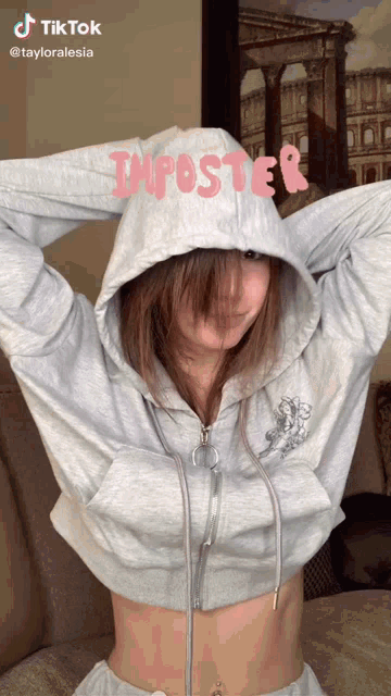 a girl wearing a grey hoodie with imposter written on it