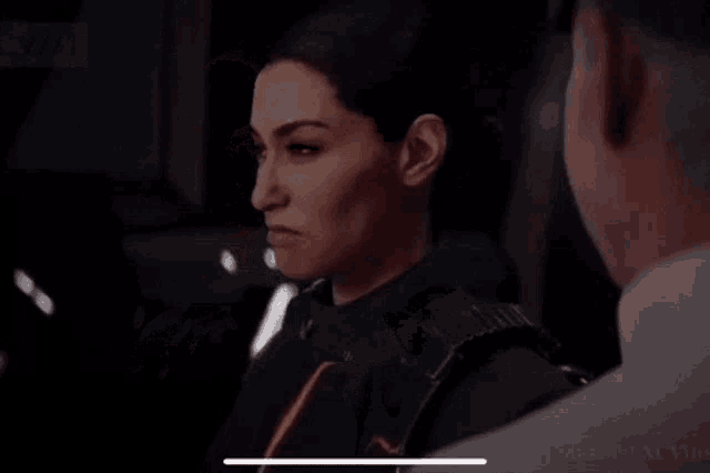a woman is standing next to a man in a dark room and looking at him .