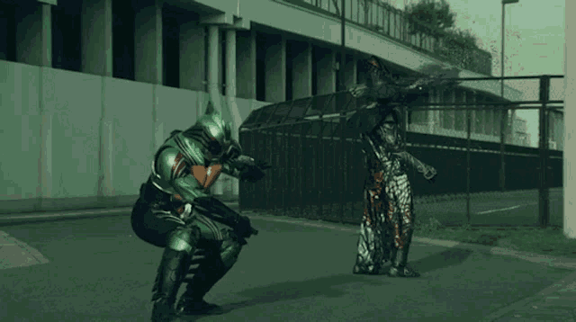 a man in a green armor is kneeling down next to another man in a black armor
