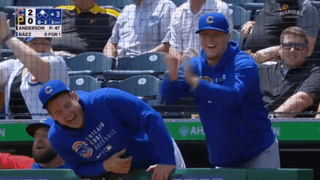 two chicago cubs players laughing in the dugout