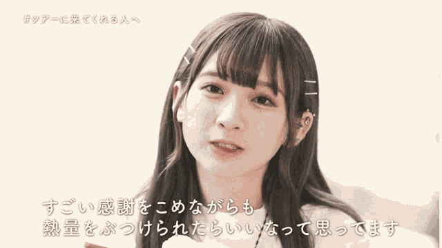 a girl with a piercing in her ear looks at the camera with chinese writing behind her .