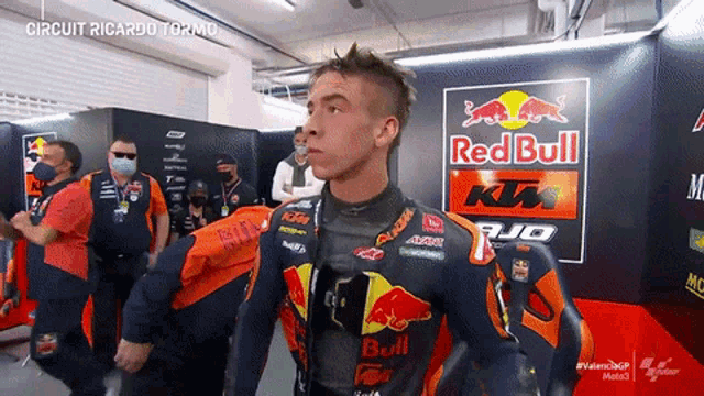 a man standing in front of a red bull ktm sign