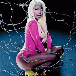 a woman in a pink bodysuit is kneeling down in front of barbed wire