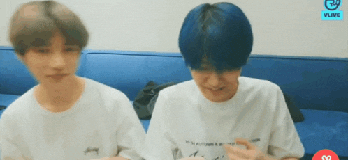 two men with blue hair are sitting next to each other on a couch .