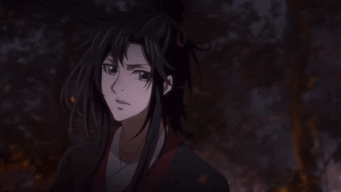 a man with long black hair is laughing in a dark room