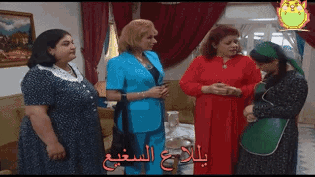 a group of women standing in a living room with arabic writing on the screen