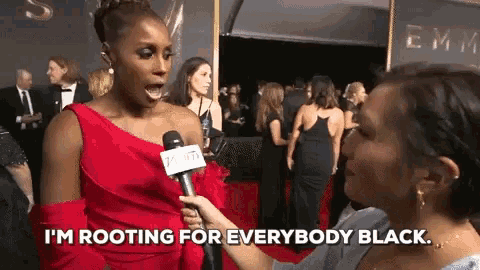 a woman in a red dress is being interviewed on the red carpet and says i 'm rooting