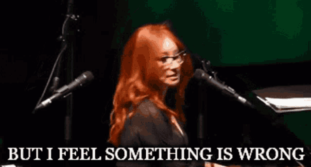 a woman singing into a microphone with the words " but i feel something is wrong " above her