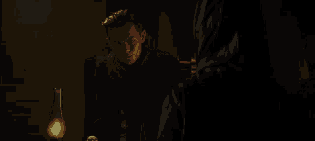 a man sits at a table in a dark room with a lamp in front of him