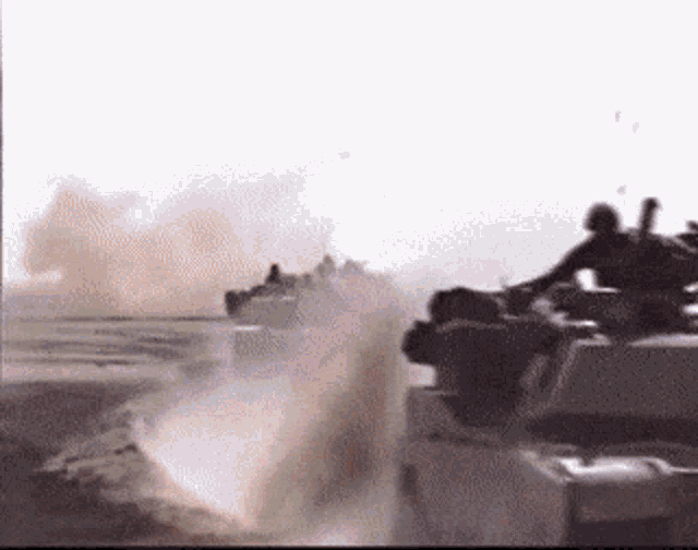 a group of military vehicles are driving down a road in the desert .