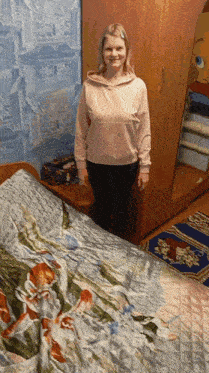 a woman is standing in front of a bed with a floral blanket