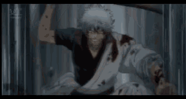 a man in a black shirt is holding a sword in his hand while another man is laying on the ground .