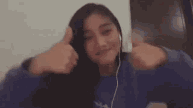 a woman is wearing headphones and giving a thumbs up sign .
