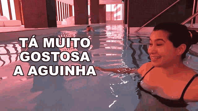 a woman is swimming in a pool with the words ta muito gostosa a aguinha