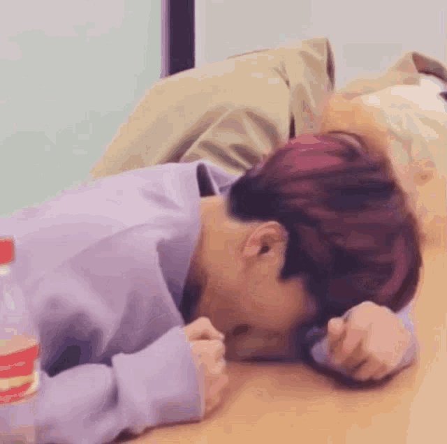 a person in a purple shirt is laying on a wooden floor
