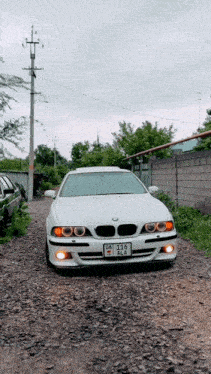a white bmw is parked on a gravel road with a license plate that says dz-215