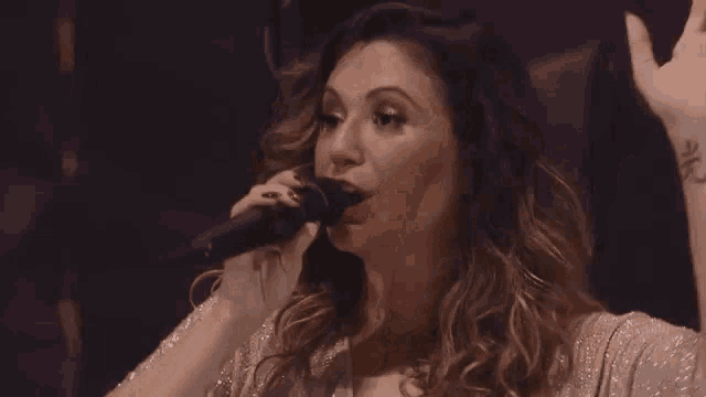 a close up of a woman singing into a microphone on a stage .