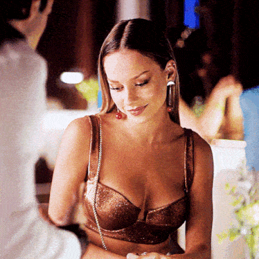 a woman in a bra and earrings is smiling and looking down