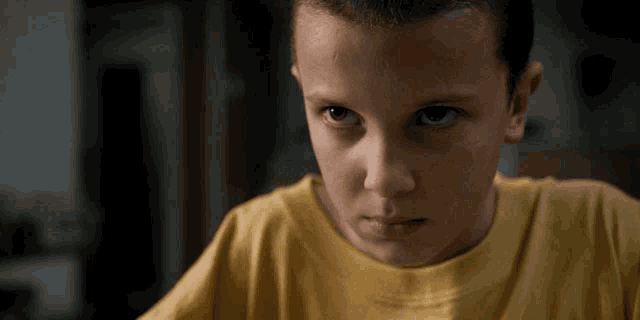 a close up of a young girl 's face with a yellow shirt on