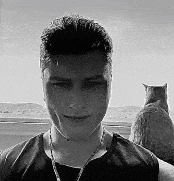 a man with a cat behind him looks at the camera
