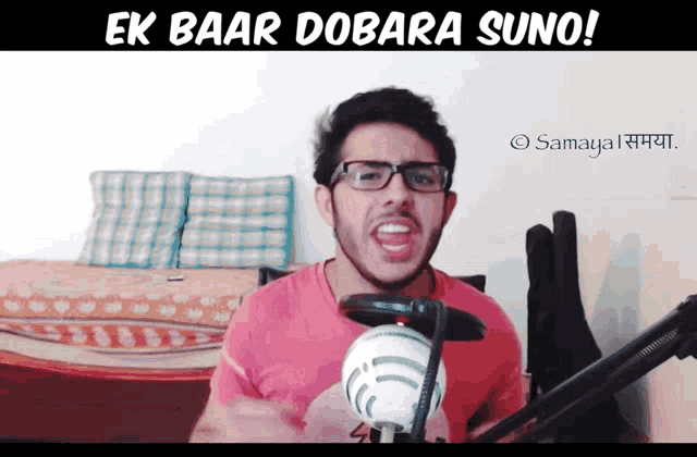 a man wearing glasses stands in front of a microphone with the words ek baar dobara suno