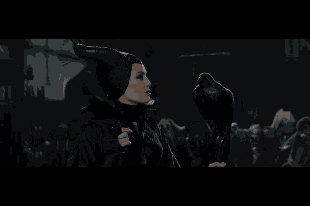 a woman in a black costume with horns holds a black bird in her hand