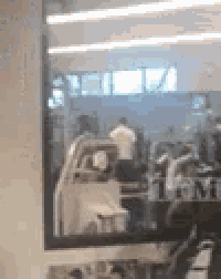 a person is sitting on a treadmill in a gym behind a glass door .