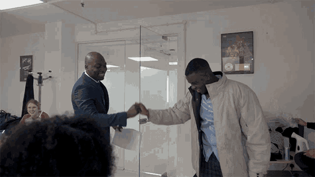 a man in a white jacket shakes hands with another man in a blue jacket