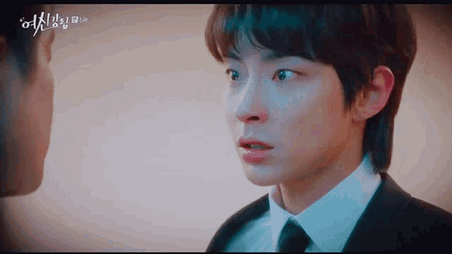 a man in a suit and tie is looking at another man