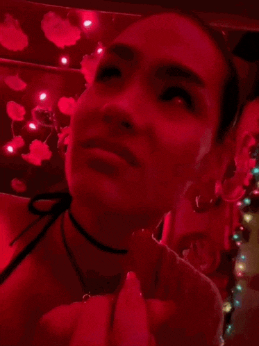 a close up of a woman 's face in a dark room with red lights .