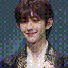 a close up of a young man wearing a black jacket and a white shirt smiling .